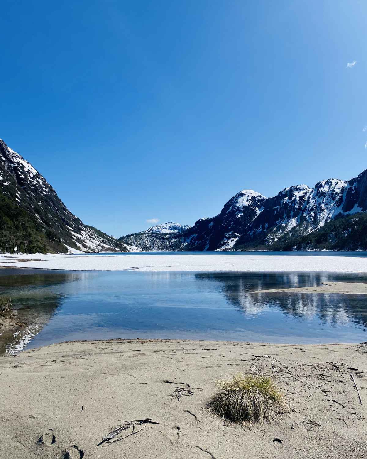 Lago de montaña con nieve y cielo azul