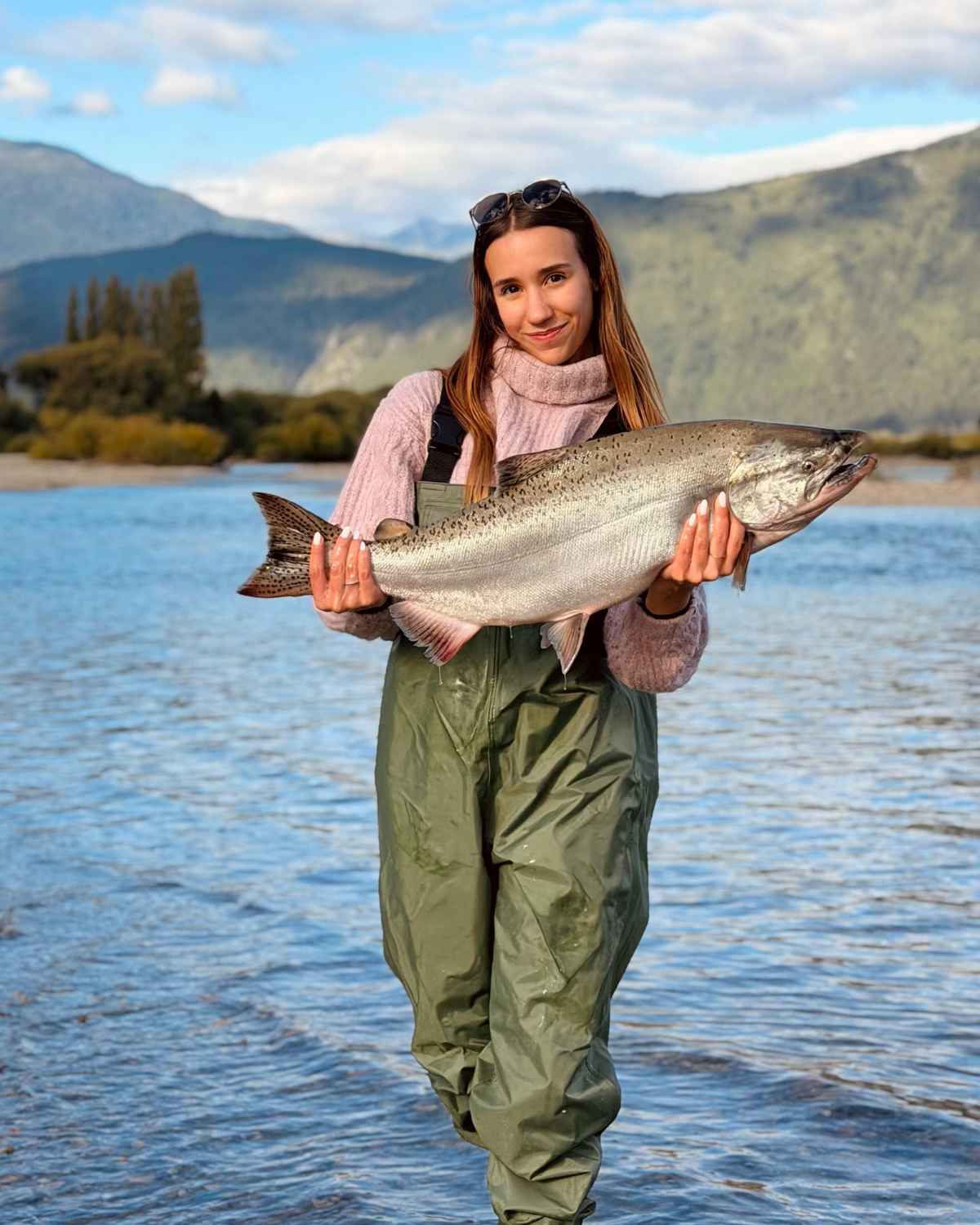 Pescadora sosteniendo un gran salmón en el río