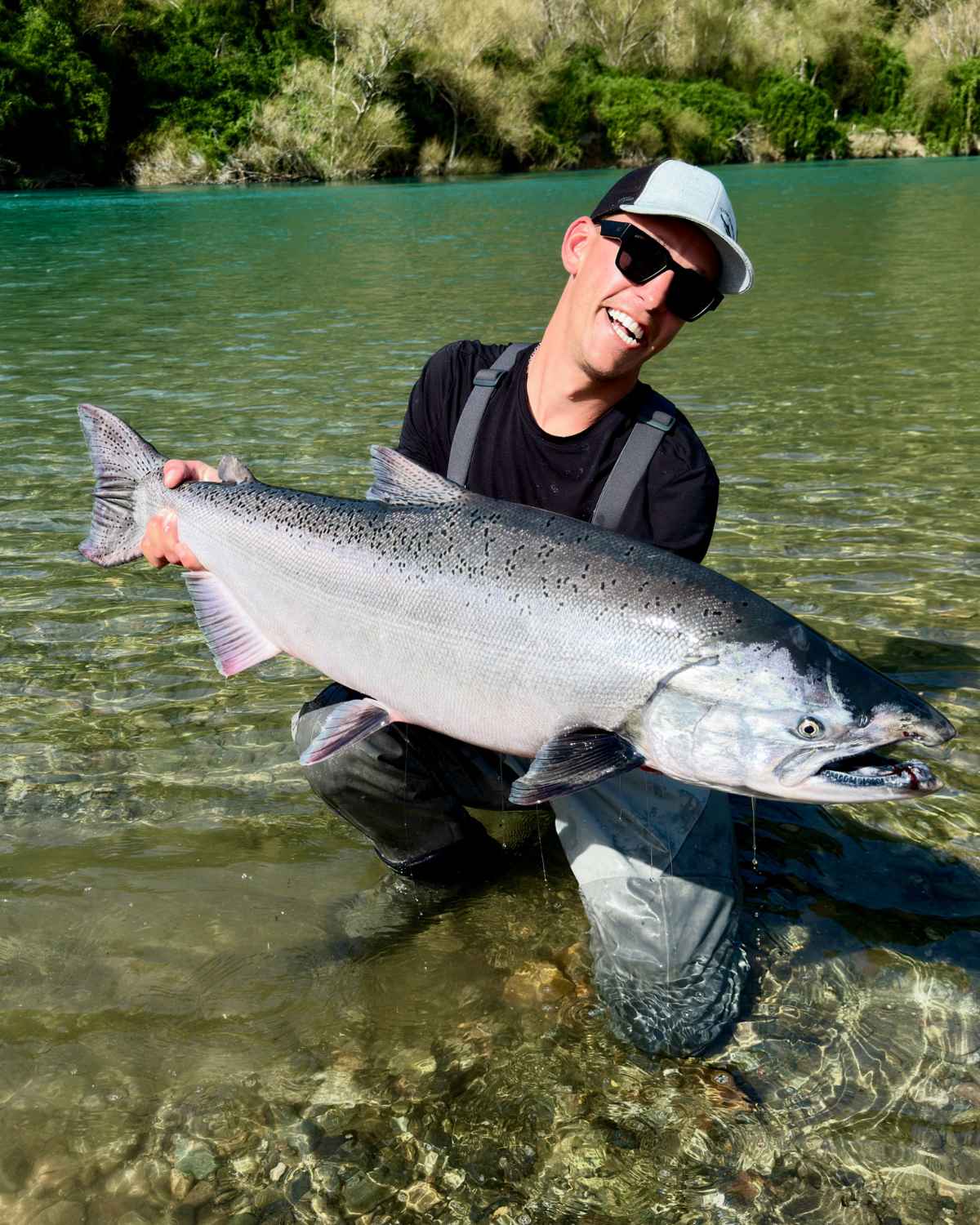 Pescador con un gran salmón Chinook en un río turquesa de la Patagonia