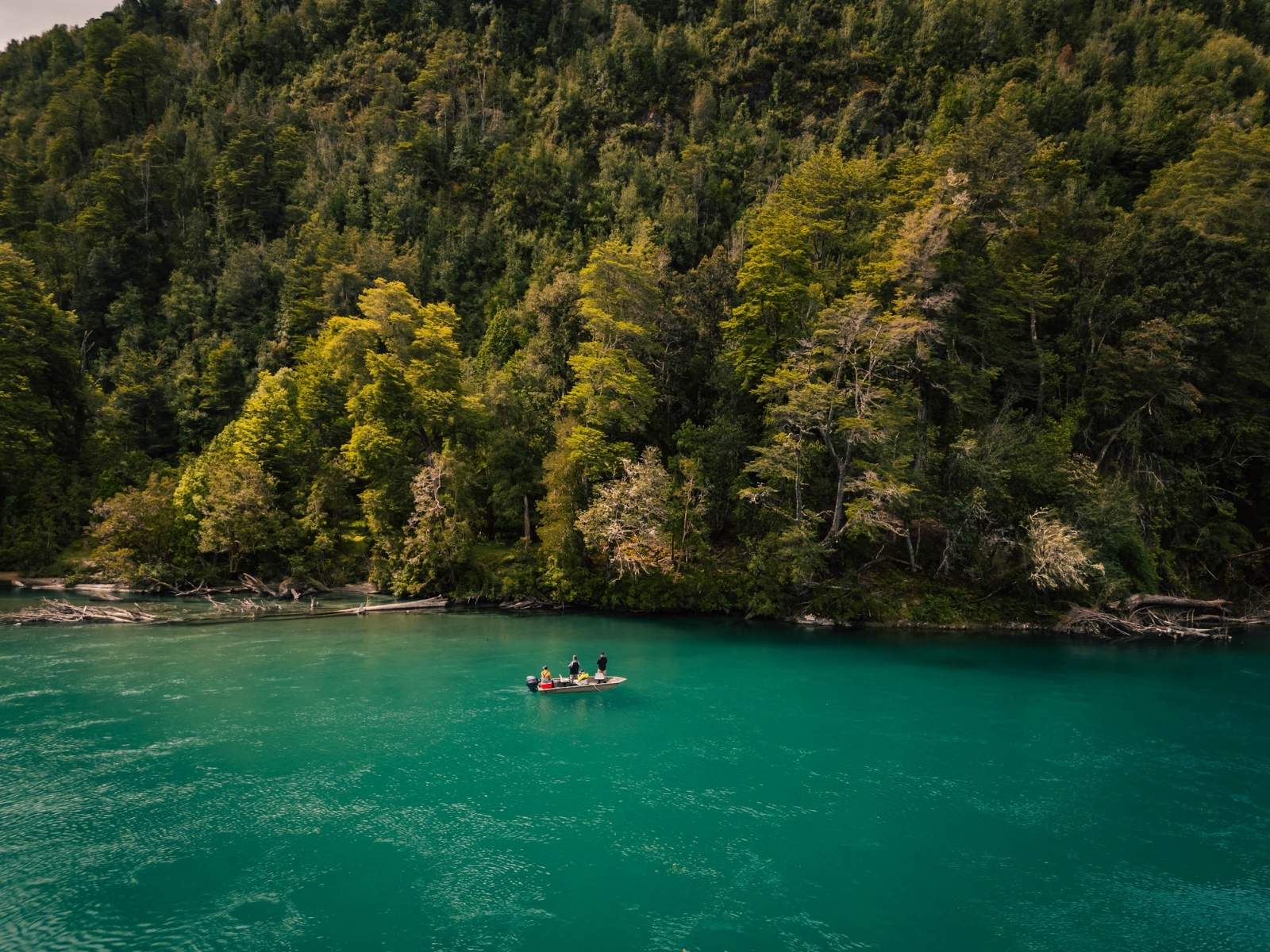 Guía y pescadores en un bote sobre un río turquesa de la Patagonia