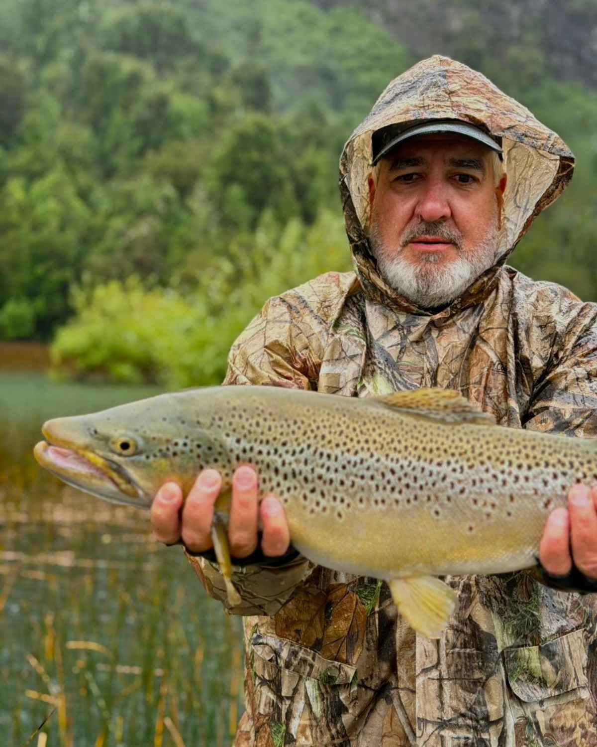 Pescador sosteniendo una hermosa trucha marrón de gran tamaño